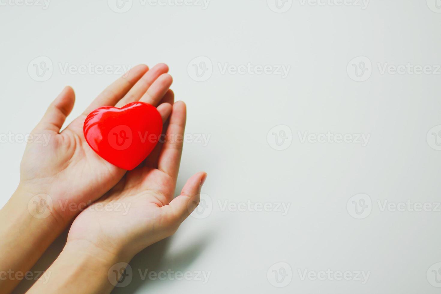 een vrouw die een rood hart op haar handpalm zet met een witte achtergrond. donatie idee foto