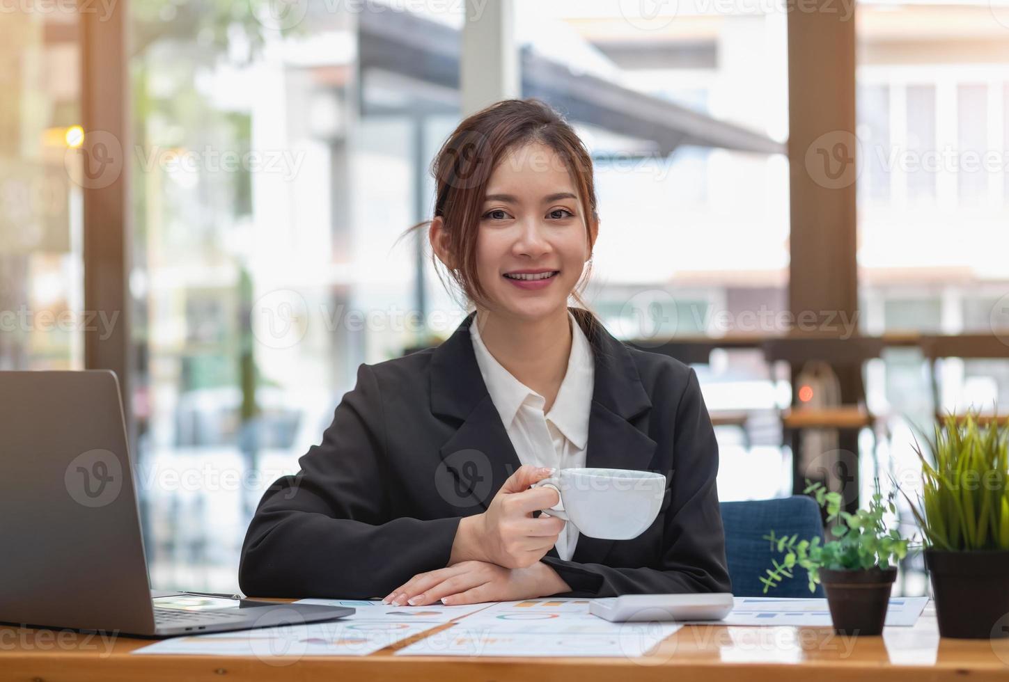 marketing, financiën, boekhouding, planning, zakenvrouw met een kopje koffie online vergadering winstanalyse met grafiekstatistieken gebruik een laptop en een rekenmachine om uw bedrijfssaldo te berekenen. foto