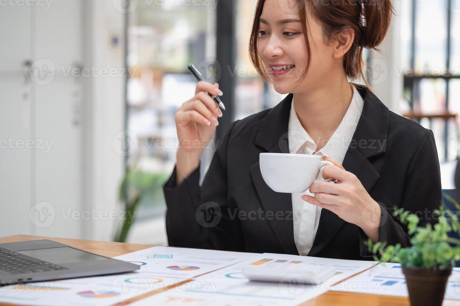 marketing, financiën, boekhouding, planning, zakenvrouw met een kopje koffie online vergadering winstanalyse met grafiekstatistieken gebruik een laptop en een rekenmachine om uw bedrijfssaldo te berekenen. foto