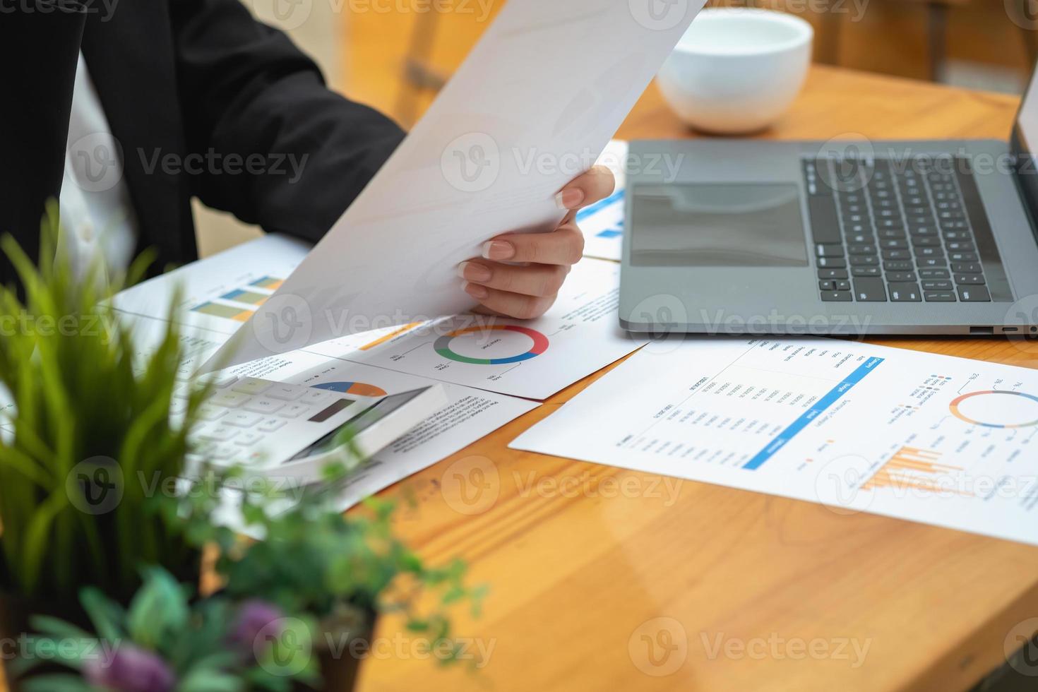 marketing, financieel, boekhouding, planning, zakenvrouwen analyseren bedrijfsresultaten en winst met grafiekstatistieken. gebruik een laptop en een rekenmachine om het saldo van het bedrijf te berekenen. foto