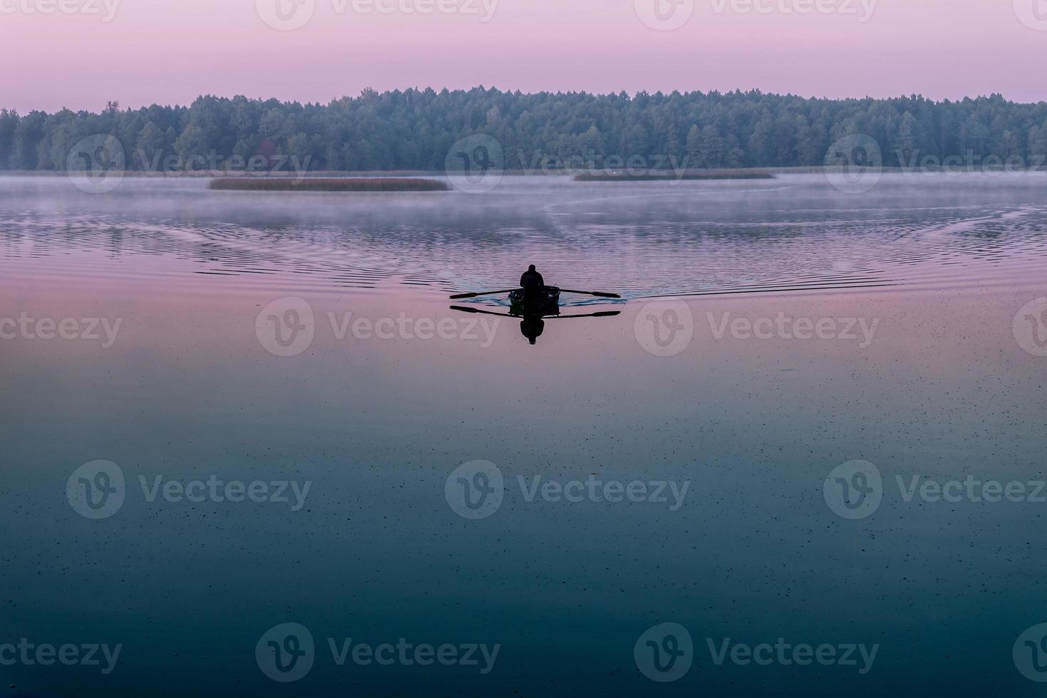 silhouet van de mens in een boot in de vroege ochtend. roze dageraad foto