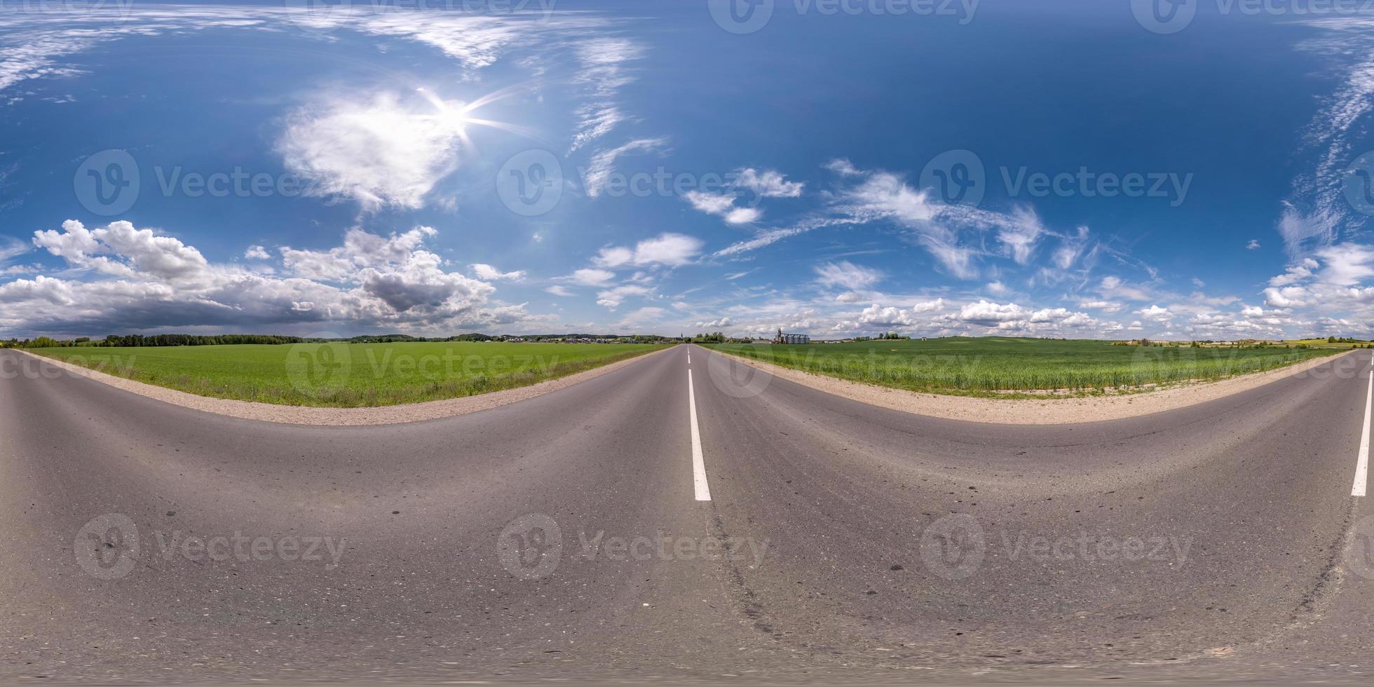 volledig bolvormig naadloos hdri-panorama 360 graden hoekzicht op asfaltweg zonder verkeer tussen velden met heldere blauwe lucht in equirectangular projectie, vr ar-inhoud foto