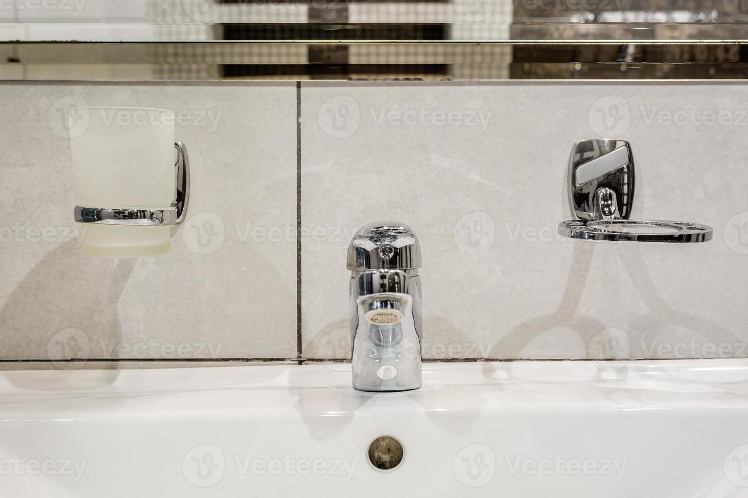 zeep- en shampoodispensers in de buurt van keramische waterkraangootsteen met kraan in dure loftbadkamer foto