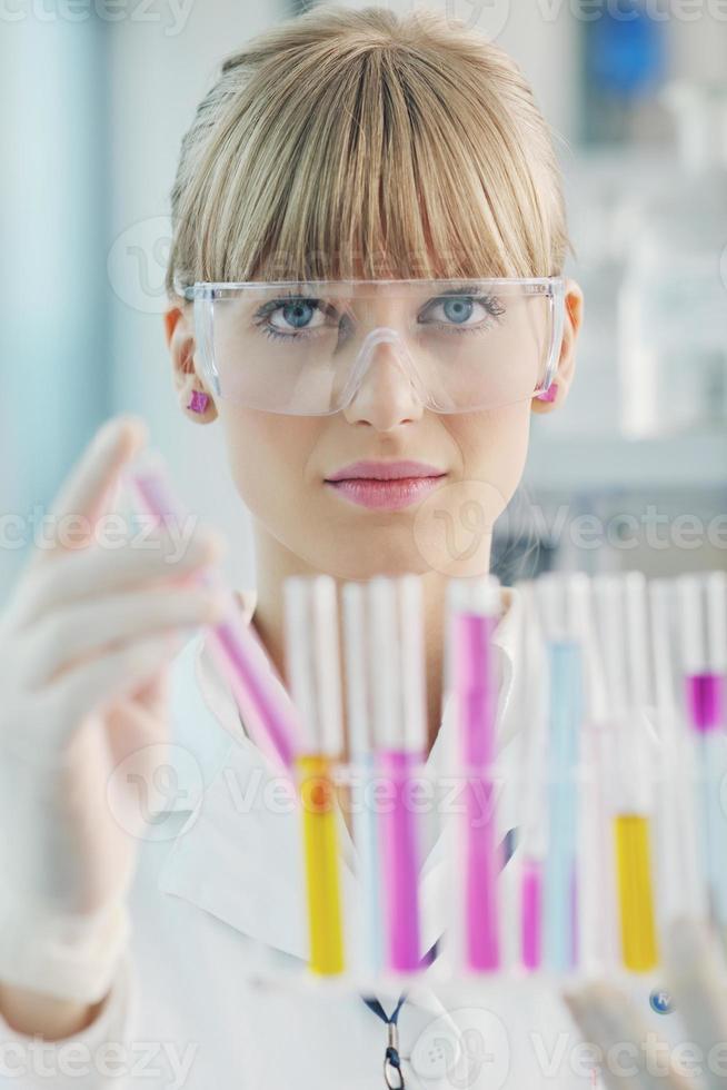 vrouwelijke onderzoeker die een reageerbuis in laboratorium steunt foto