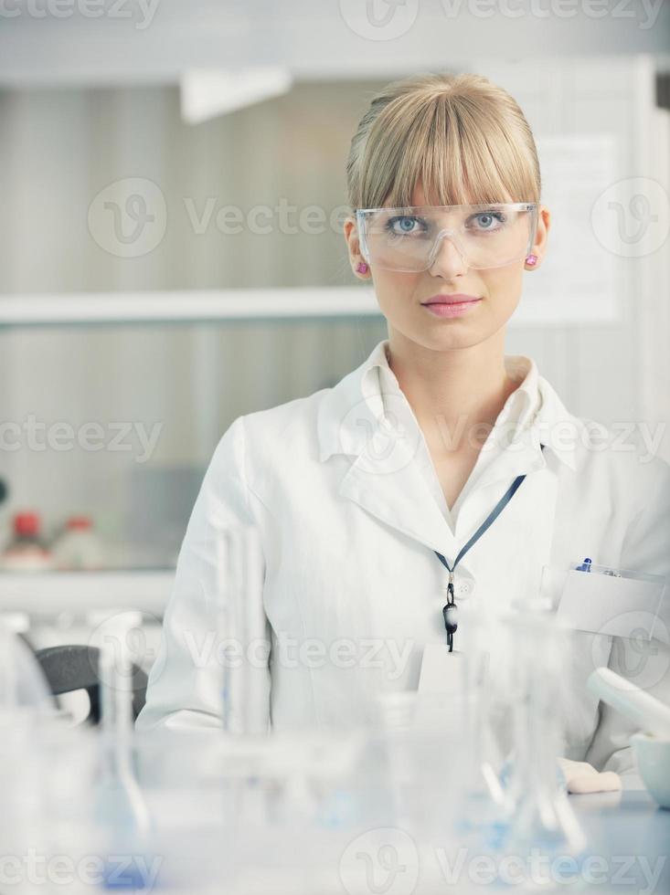 vrouwelijke onderzoeker die een reageerbuis in laboratorium steunt foto