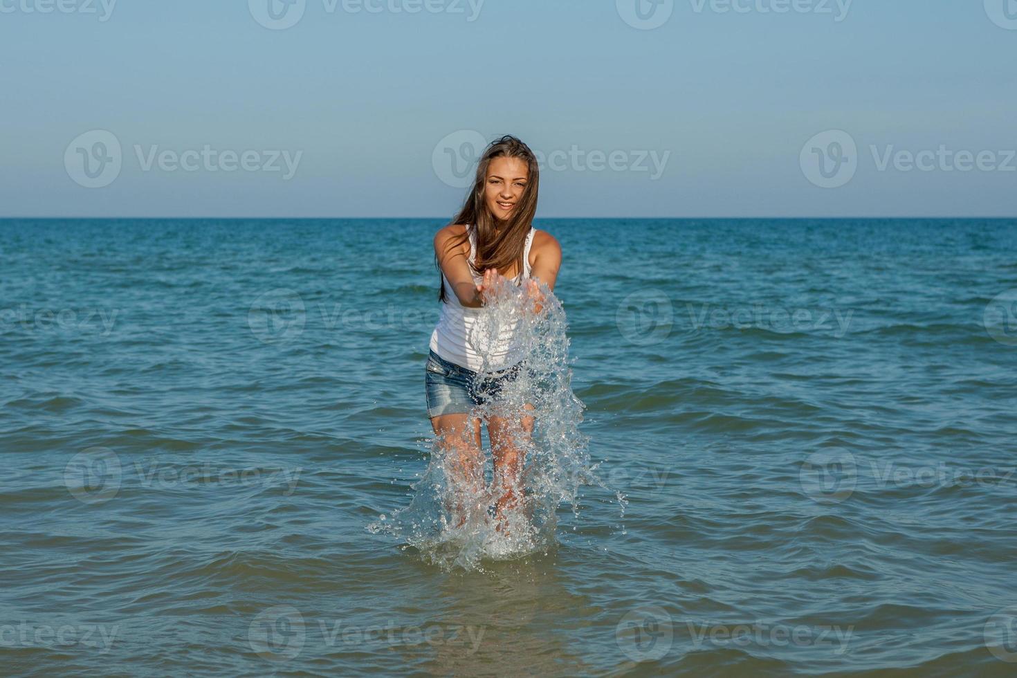 jong meisje spettert het water in de zee foto