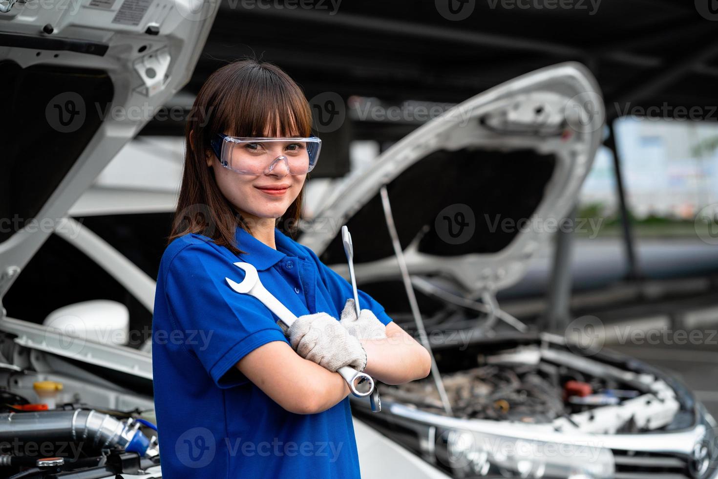 vrouwelijke monteur die in een garage voor automonteur werkt. een vrouwelijke monteur repareert de auto van een klant bij een autoservicecentrum. auto keuring. auto reparatie winkel. dienstverleningsconcept. auto reparatie dienstverleningsconcept. foto