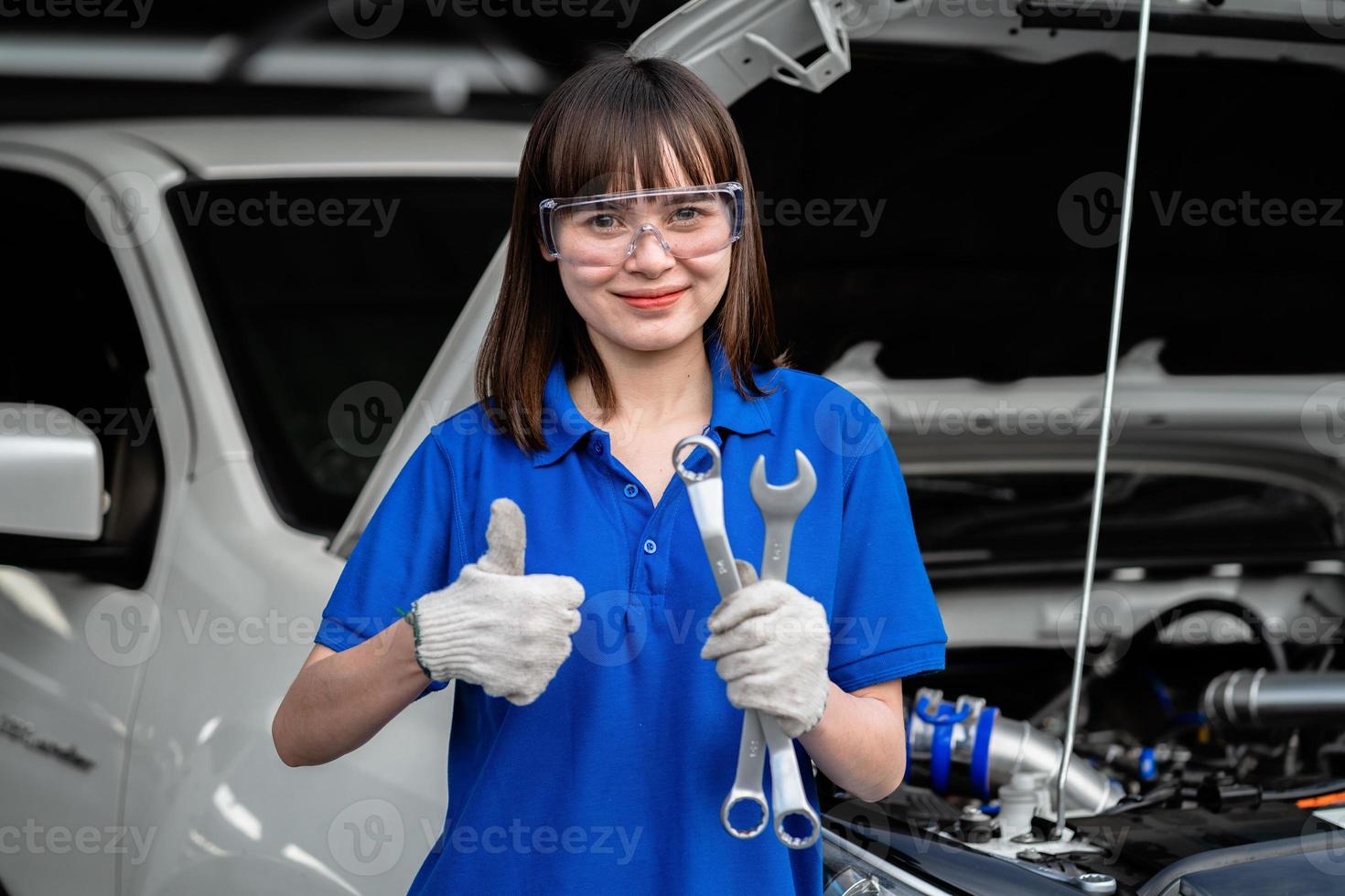 vrouwelijke monteur die in een garage voor automonteur werkt. een vrouwelijke monteur repareert de auto van een klant bij een autoservicecentrum. auto keuring. auto reparatie winkel. dienstverleningsconcept. auto reparatie dienstverleningsconcept. foto