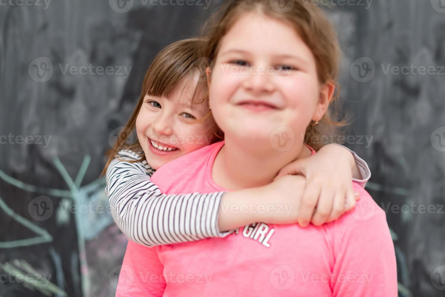 kleine meisjes knuffelen voor schoolbord foto