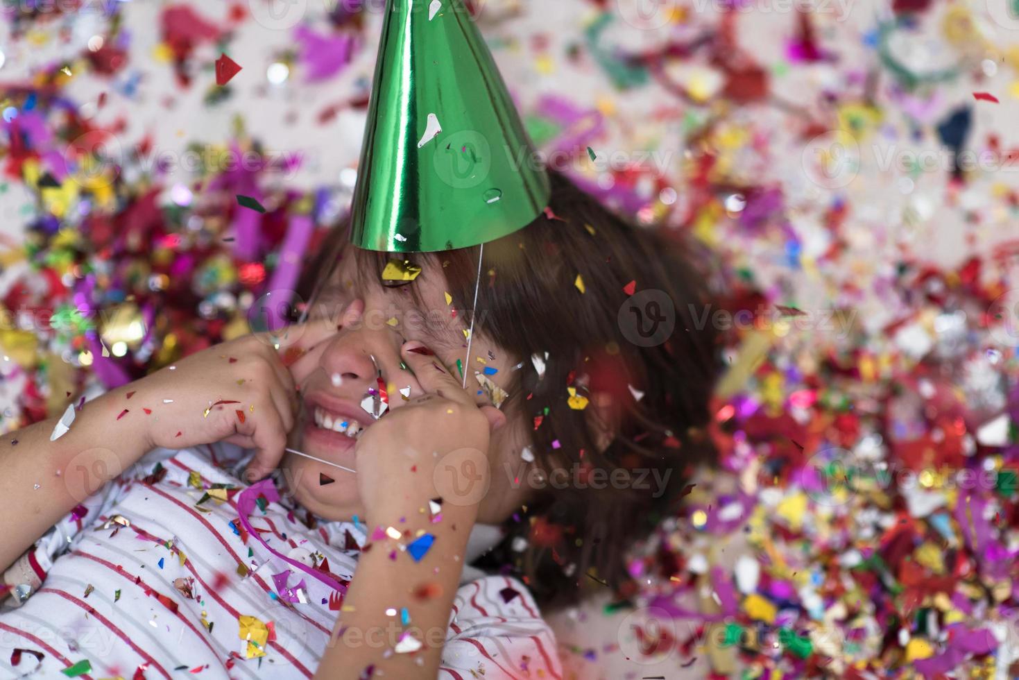 kind blaast confetti terwijl het op de grond ligt foto