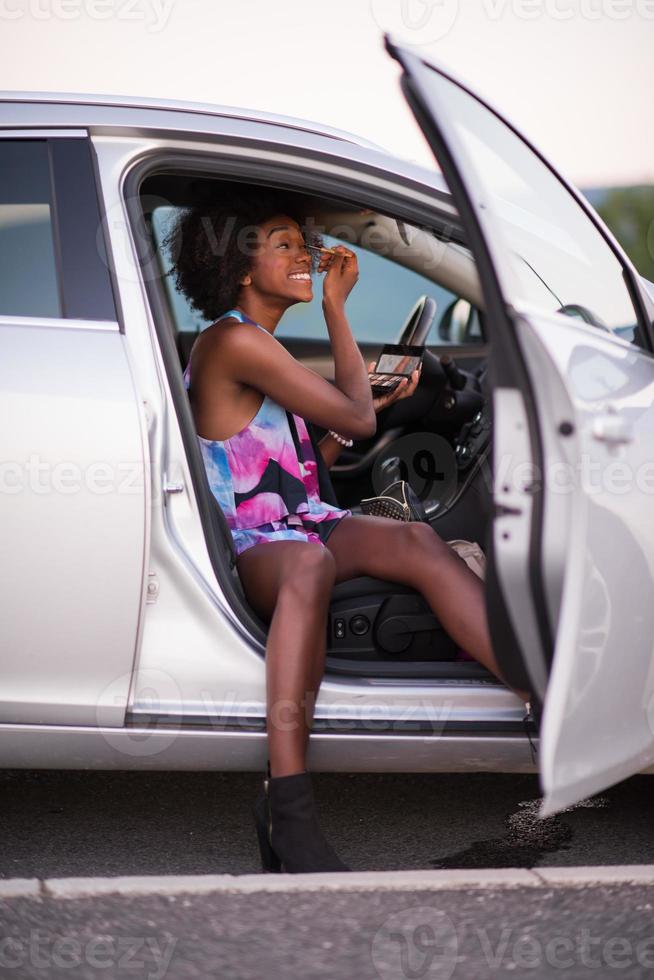 een jonge Afro-Amerikaanse vrouw make-up in de auto foto