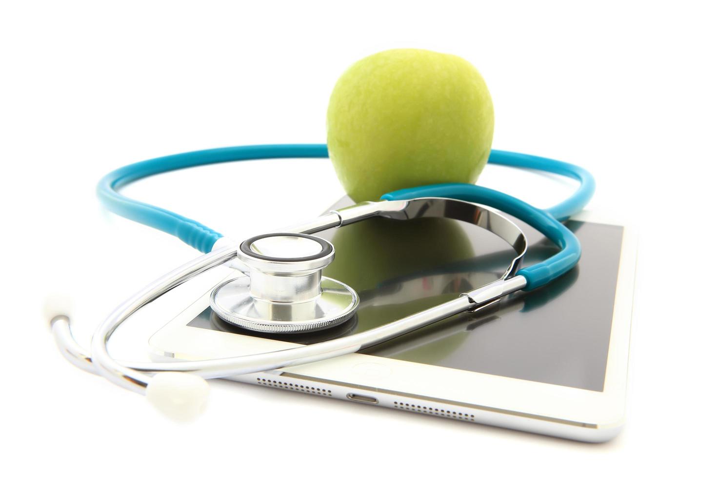 stethoscoop en groene appel geïsoleerd op tablet foto