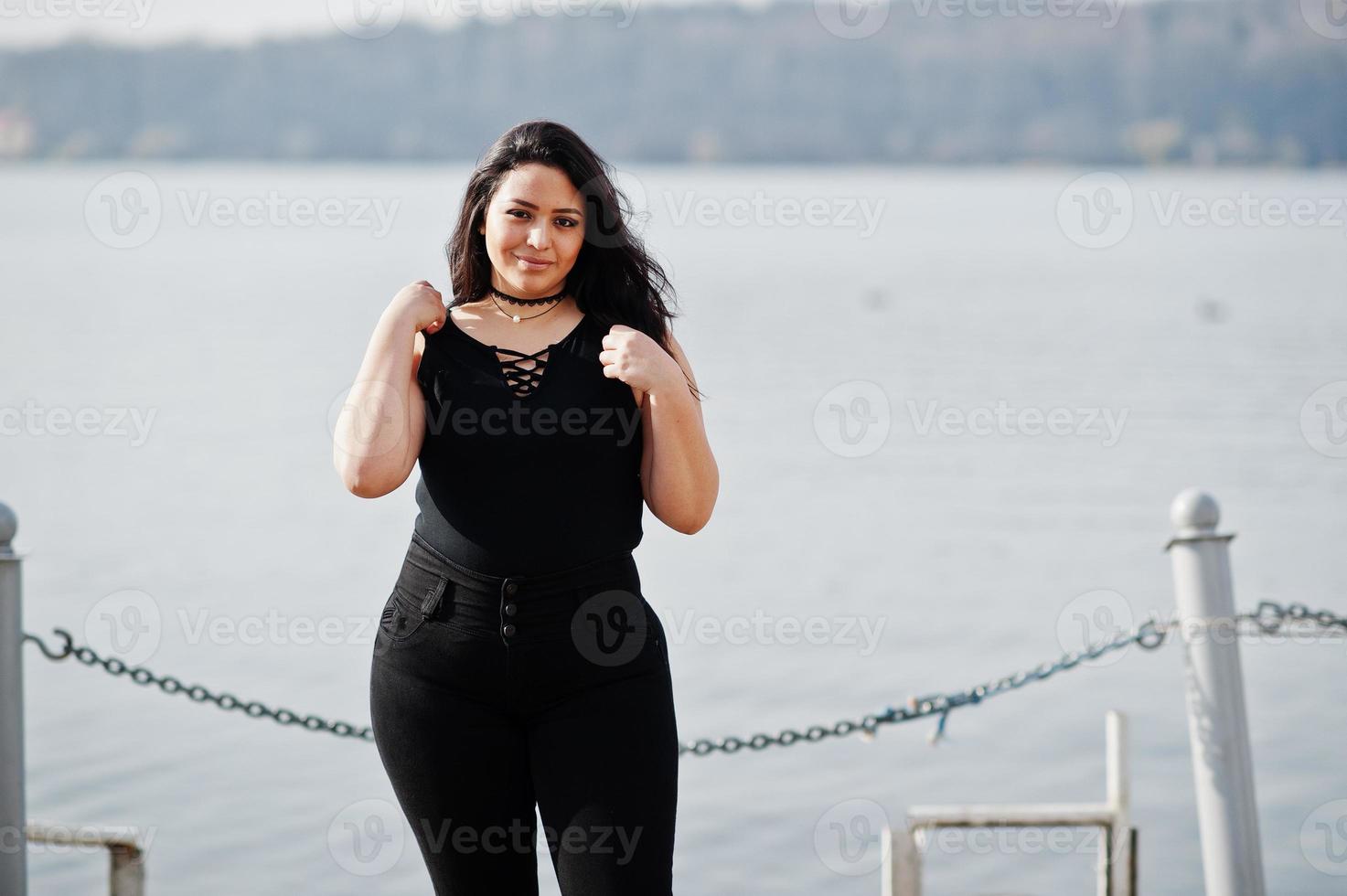 mooie latino model meisje uit ecuador slijtage op zwart gesteld tegen meer. foto