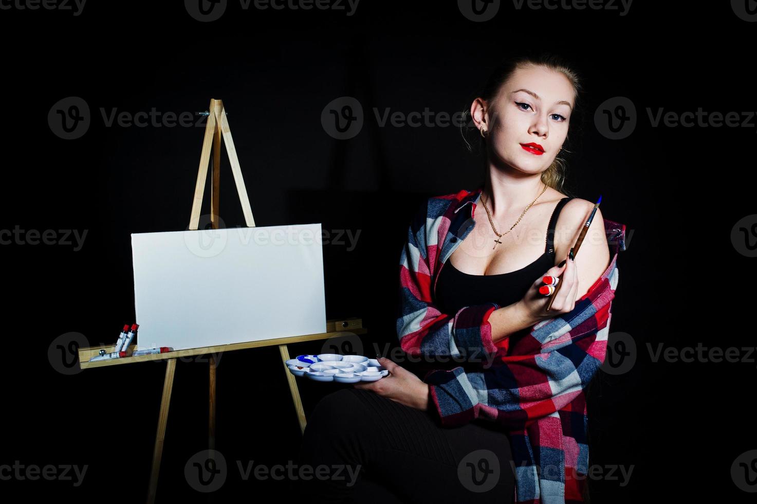 mooie vrouw kunstenaar schilder met borstels en olie canvas poseren in studio geïsoleerd op zwart. foto
