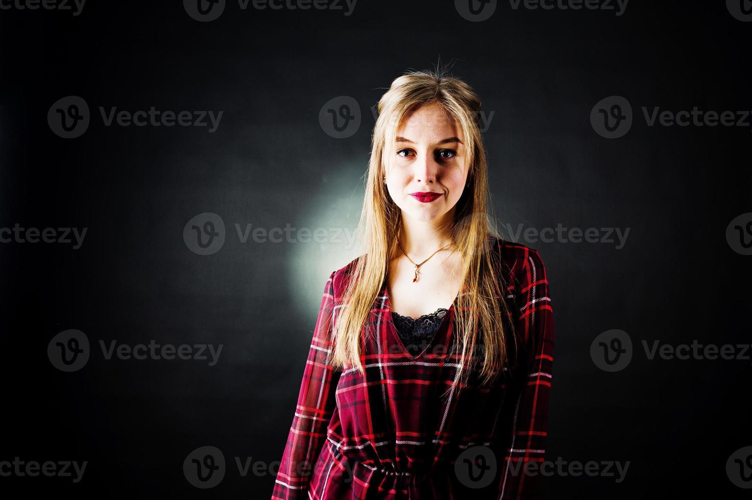 jonge blonde meisje in geruite jurk op zwarte achtergrond. foto