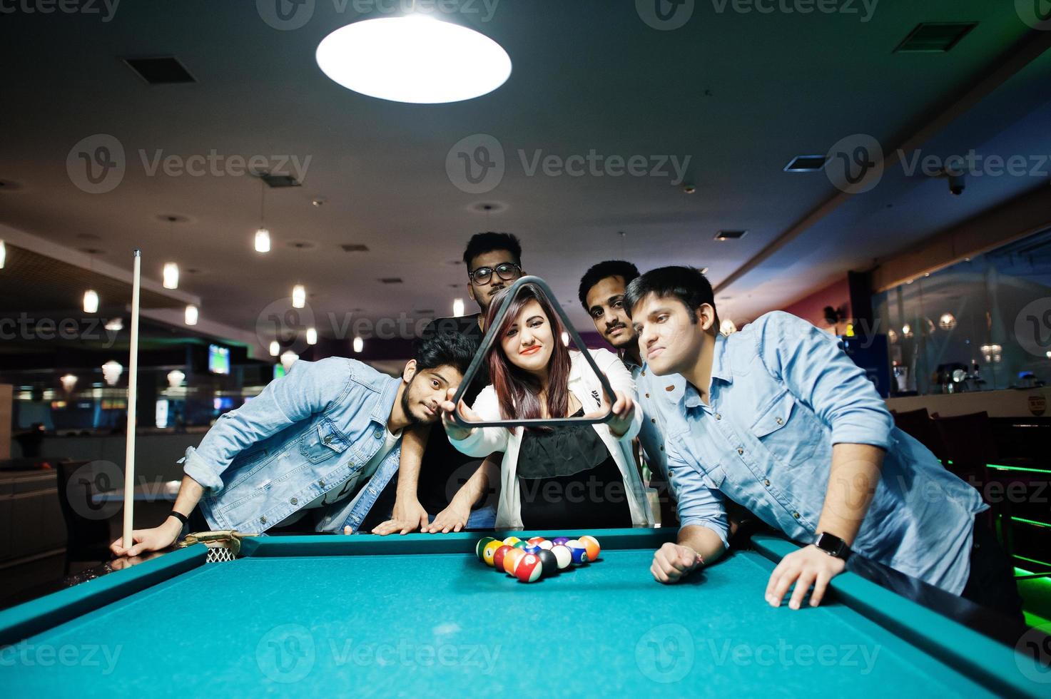 groep stijlvolle aziatische vrienden dragen jeans die poolbiljart spelen op de bar. foto