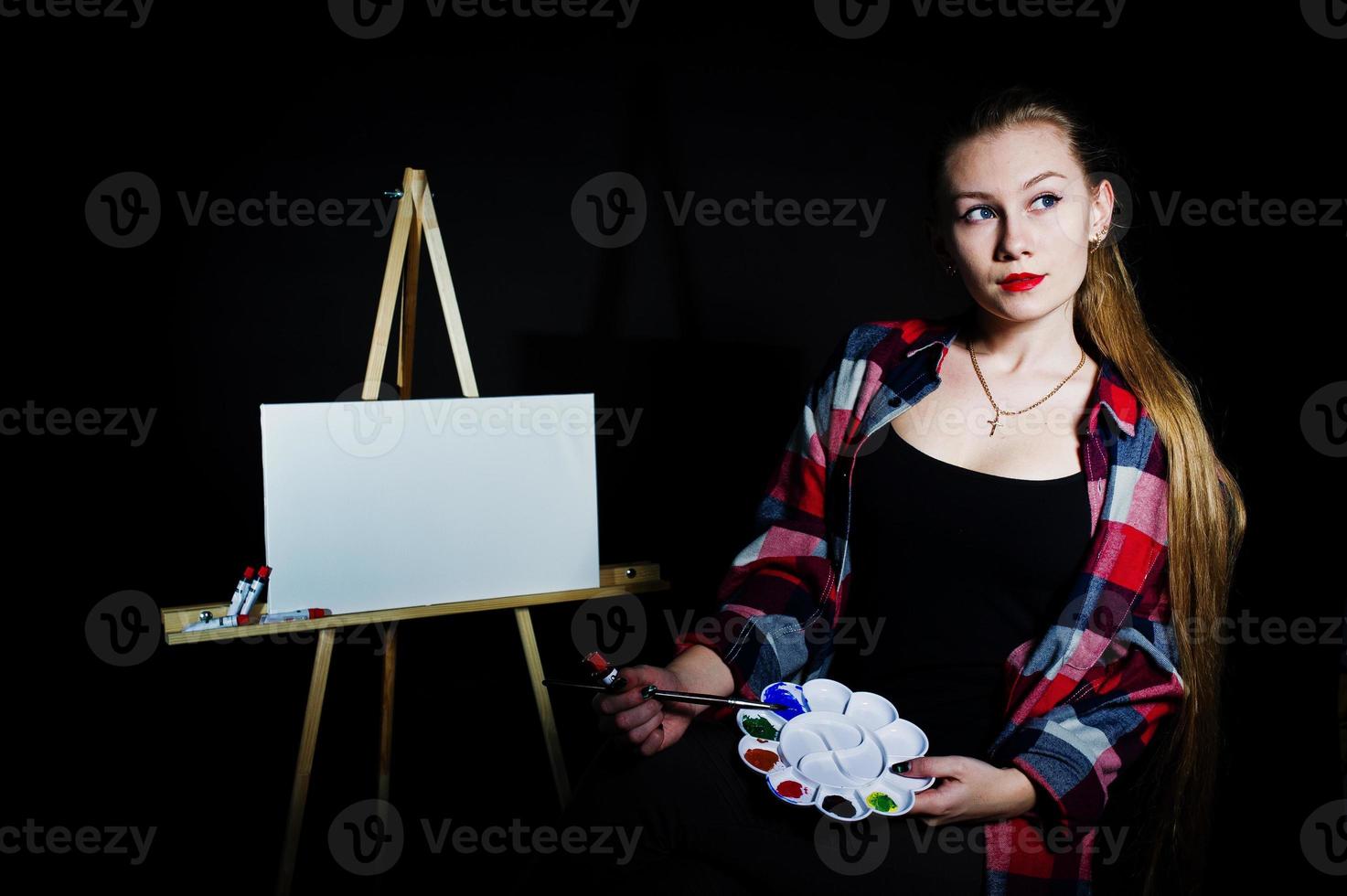 mooie vrouw kunstenaar schilder met borstels en olie canvas poseren in studio geïsoleerd op zwart. foto