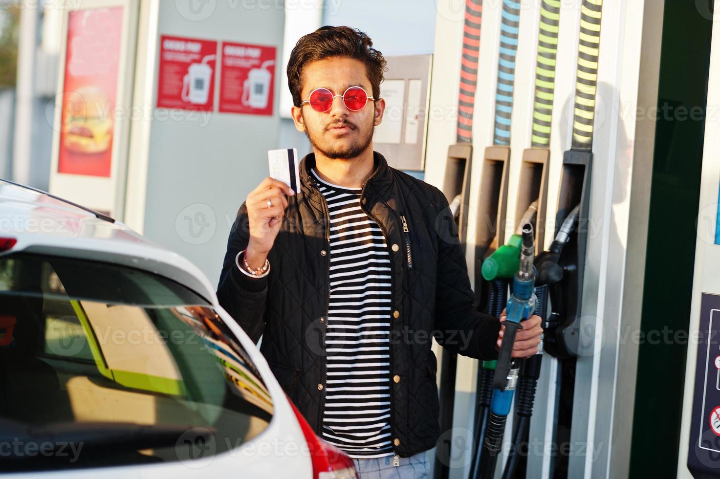 Zuid-Aziatische man of Indiase man tanken zijn witte auto op benzinestation en creditcard vasthouden. foto