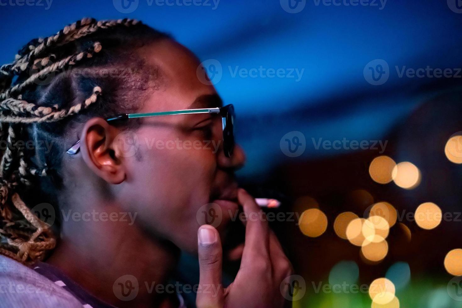 Afro-Amerikaanse man die 's nachts een sigaret rookt foto