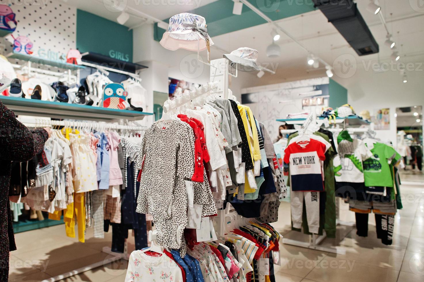 lichte kinderkleding hangt op het display in de babykledingwinkel. foto