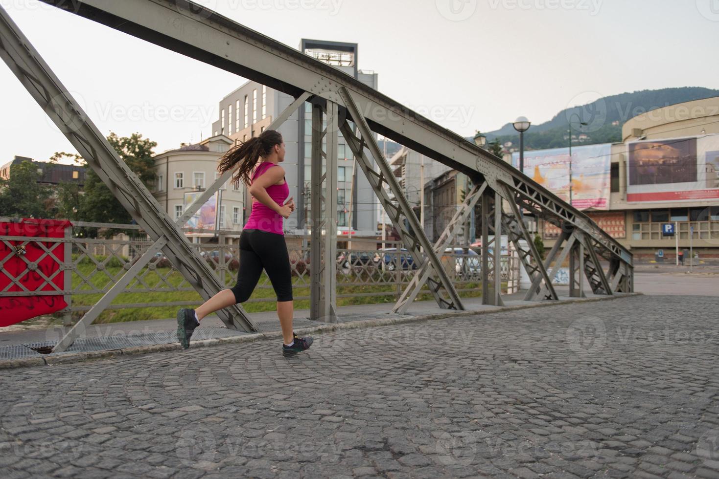 vrouw joggen over de brug op zonnige ochtend foto