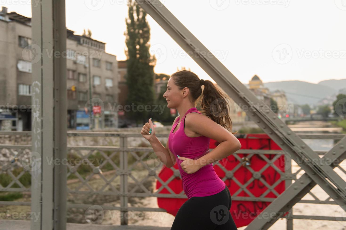 vrouw joggen over de brug op zonnige ochtend foto