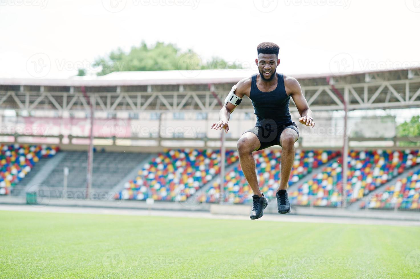 Afro-Amerikaanse mannelijke atleet in sportkleding die sprongoefening doet in het stadion. foto