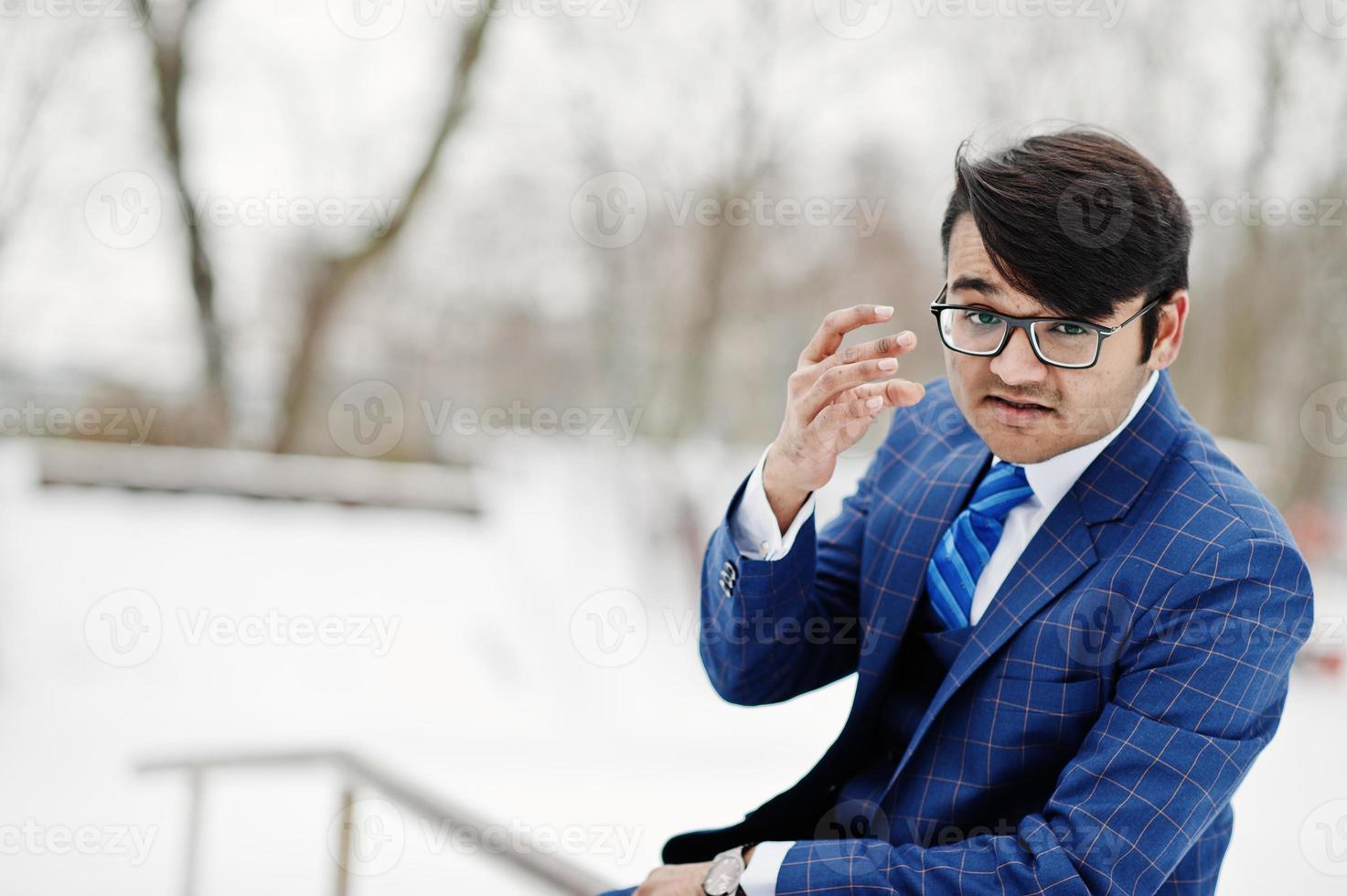 stijlvolle Indiase zakenman in pak en bril poseerde op winterdag buiten. foto