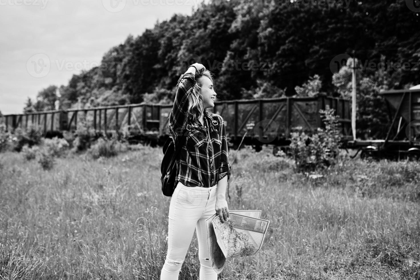 portret van een jonge blonde in tartan shirt naast de trein met een kaart. foto