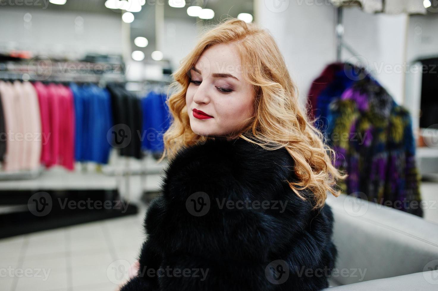 elegantie blond meisje in bontjas in de winkel van bontjassen en leren jassen. foto