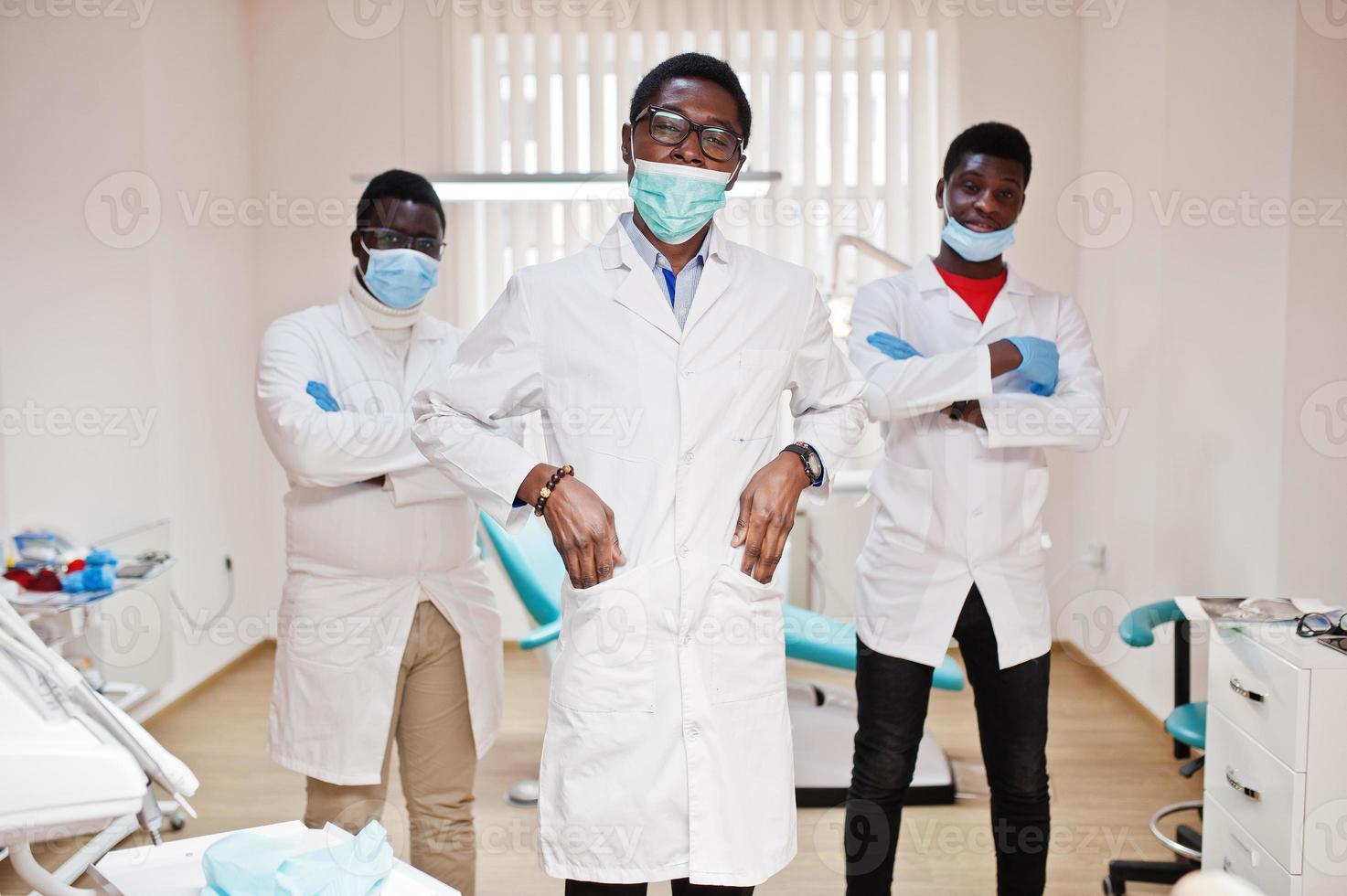 drie Afro-Amerikaanse mannelijke arts met gekruiste armen in tandheelkundige kliniek. foto