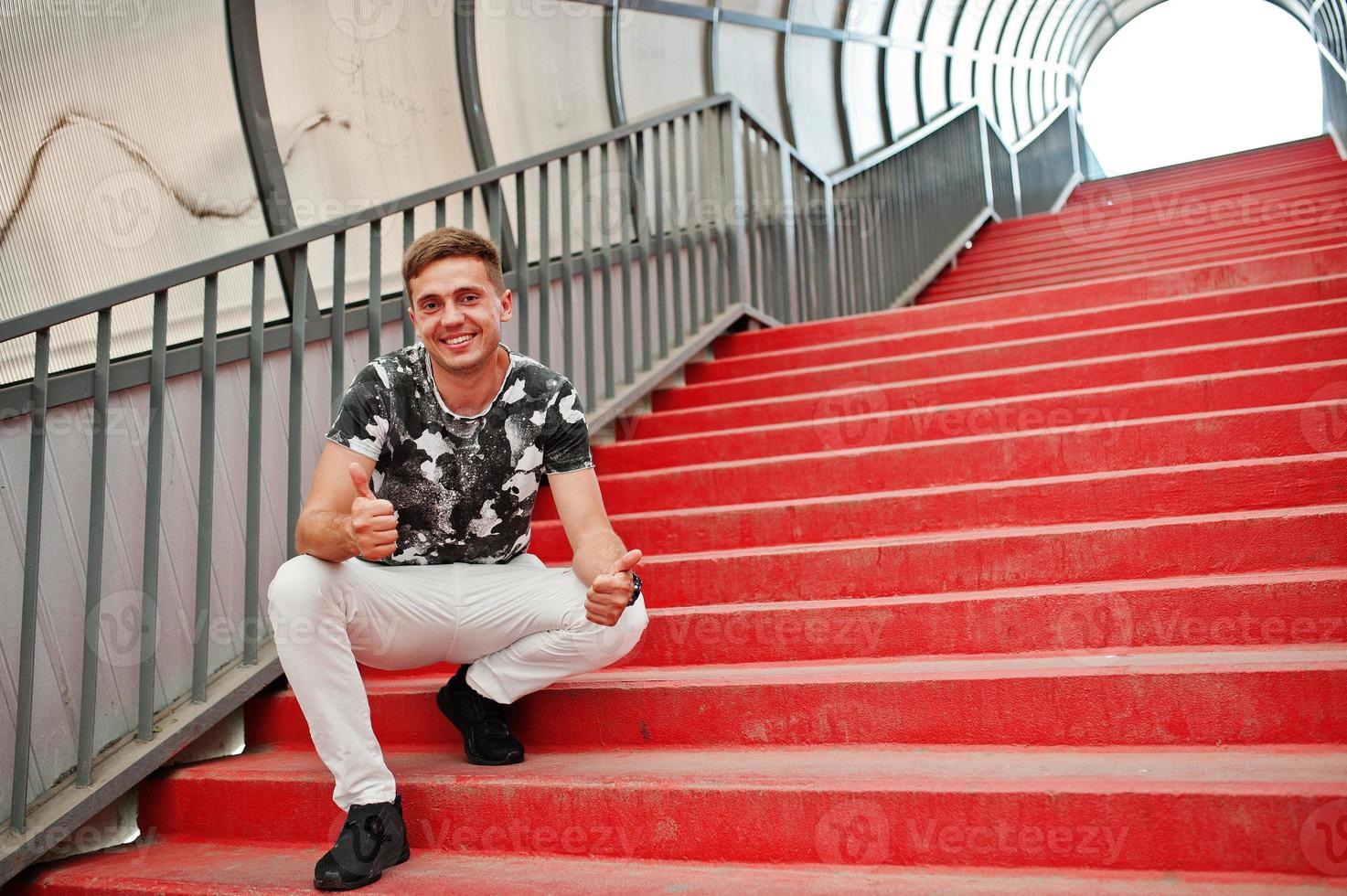 levensstijl portret van knappe man poseren in rode trappen van de stad tonel. foto