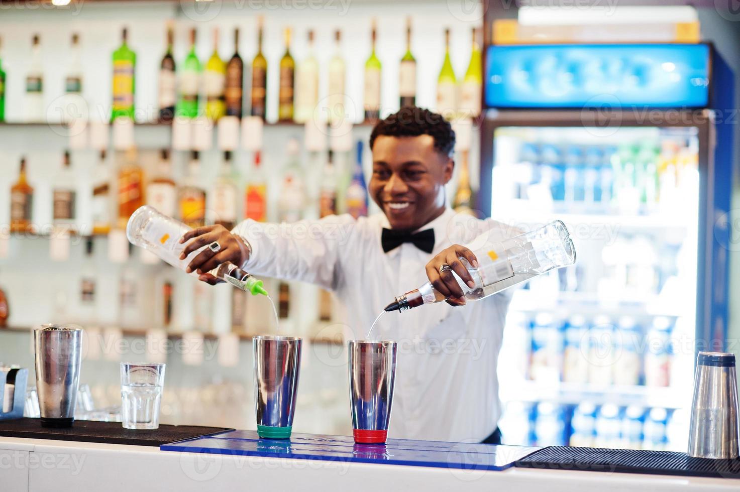 Afro-Amerikaanse barman die achter de cocktailbar werkt. bereiding van alcoholische dranken. foto