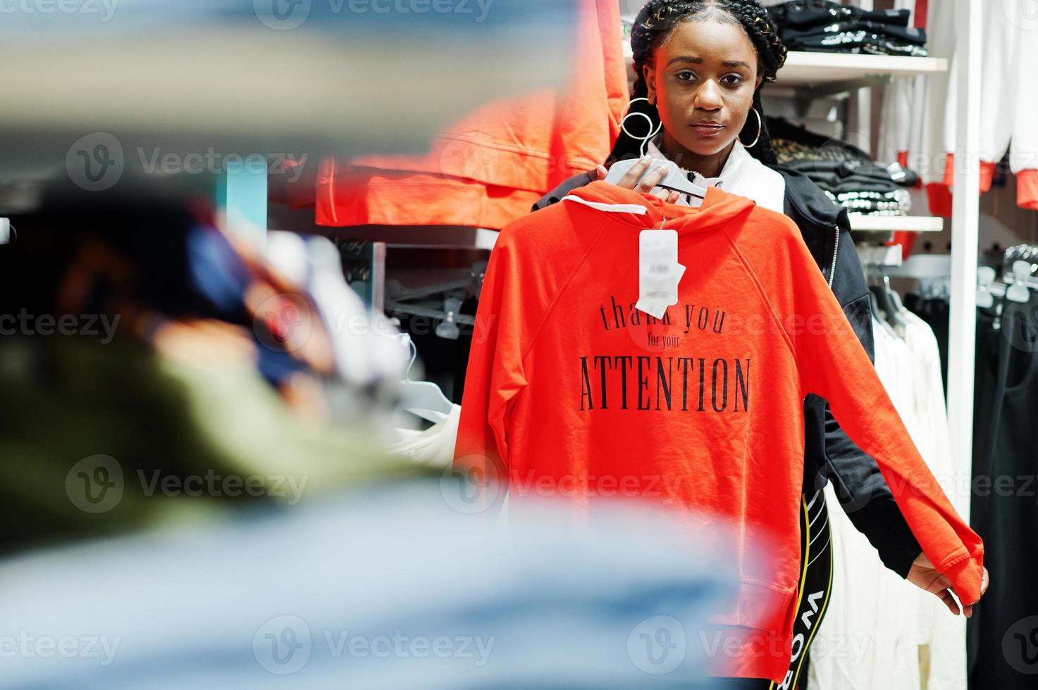 Afro-Amerikaanse vrouwen in trainingspakken winkelen bij sportkleding winkelcentrum tegen planken met sweatshirt. sport winkel thema. foto