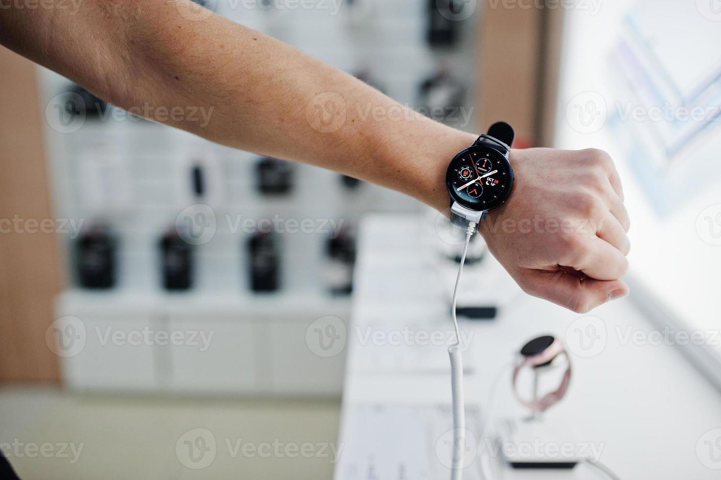 verkoper man mobiele telefoon professionele adviseur in tech winkel of winkel check nieuwe slimme horloges. foto