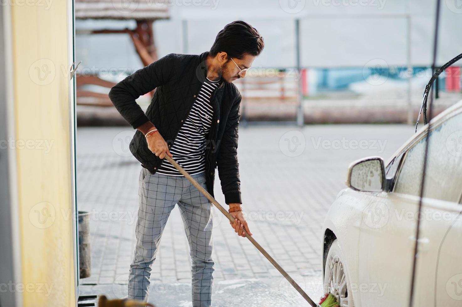Zuid-Aziatische man of Indiase man die zijn witte transport op autowasserette wast. foto