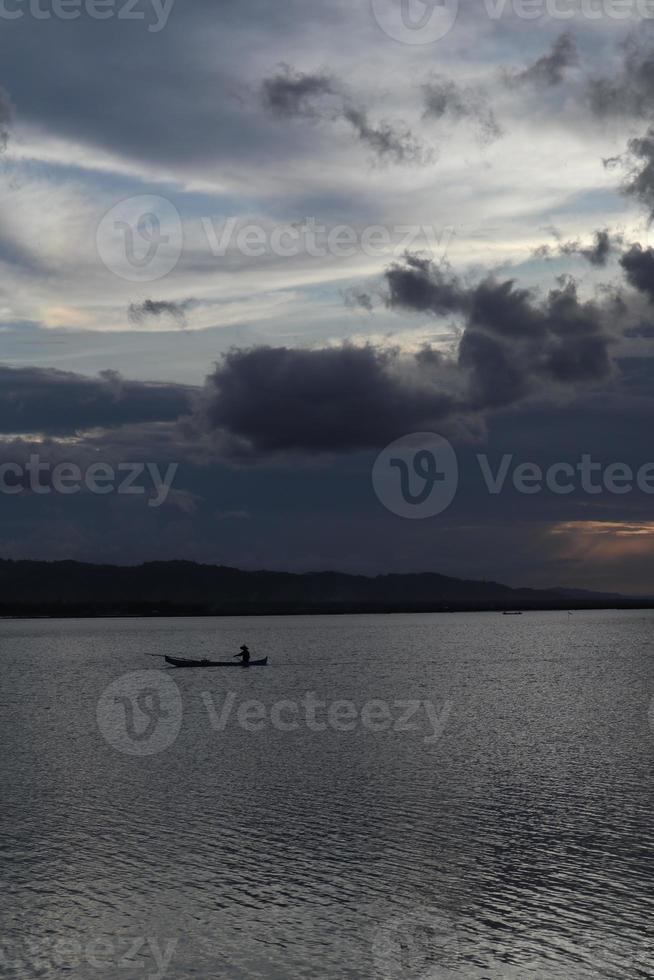 visser op zijn boot bij zonsondergang. vissersboot bij zonsondergang foto