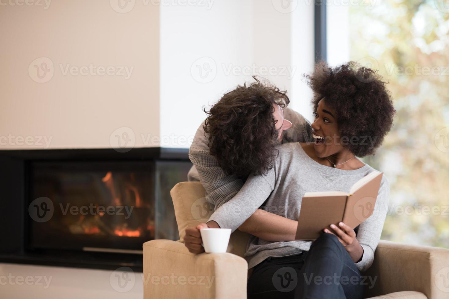 multi-etnisch paar knuffelen voor open haard foto