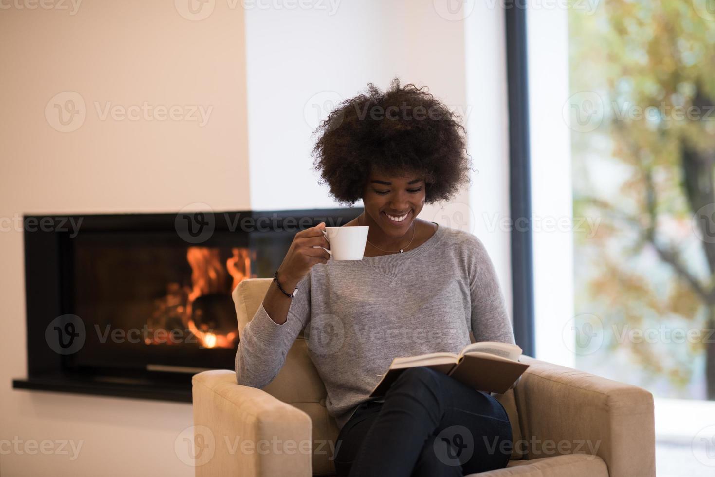 zwarte vrouw leest boek voor open haard foto