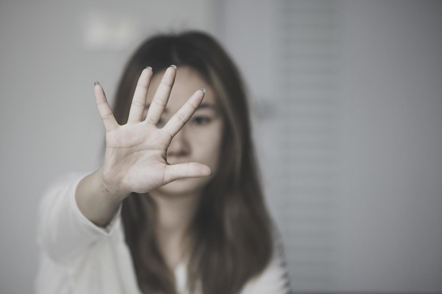 stop geweld tegen vrouwen, vrouw bedekt haar gezicht uit angst voor huiselijk geweld, donkere toon foto
