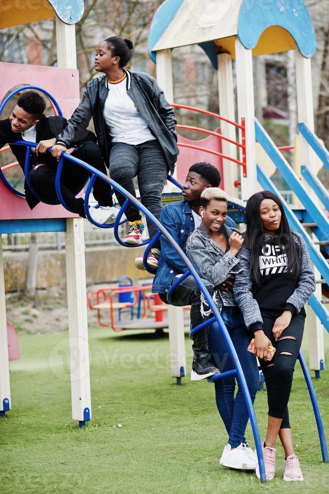 jonge millennials Afrikaanse vrienden op speelplaats, glijbaan en schommel. gelukkige zwarte mensen die samen plezier hebben. generatie z vriendschapsconcept. foto
