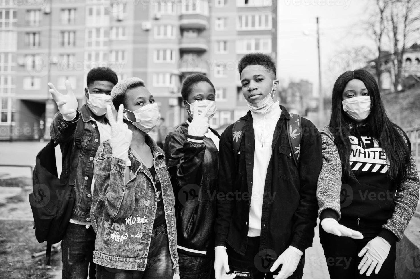 groep afrikaanse tieners vrienden tegen lege straat met gebouw met medische maskers beschermen tegen infecties en ziekten coronavirus virus quarantaine. foto
