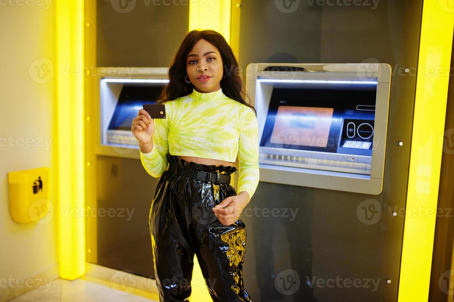 afro-amerikaanse vrouw houdt creditcard vast na het opnemen van geld uit een geldautomaat, atm-concept. foto