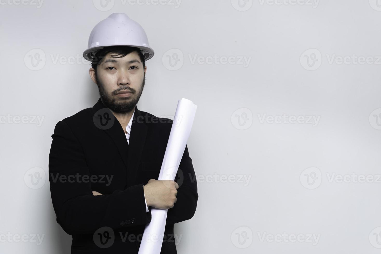 knappe aziatische ingenieur man draagt een pak, draagt een helm op een witte achtergrond, mensen uit thailand foto