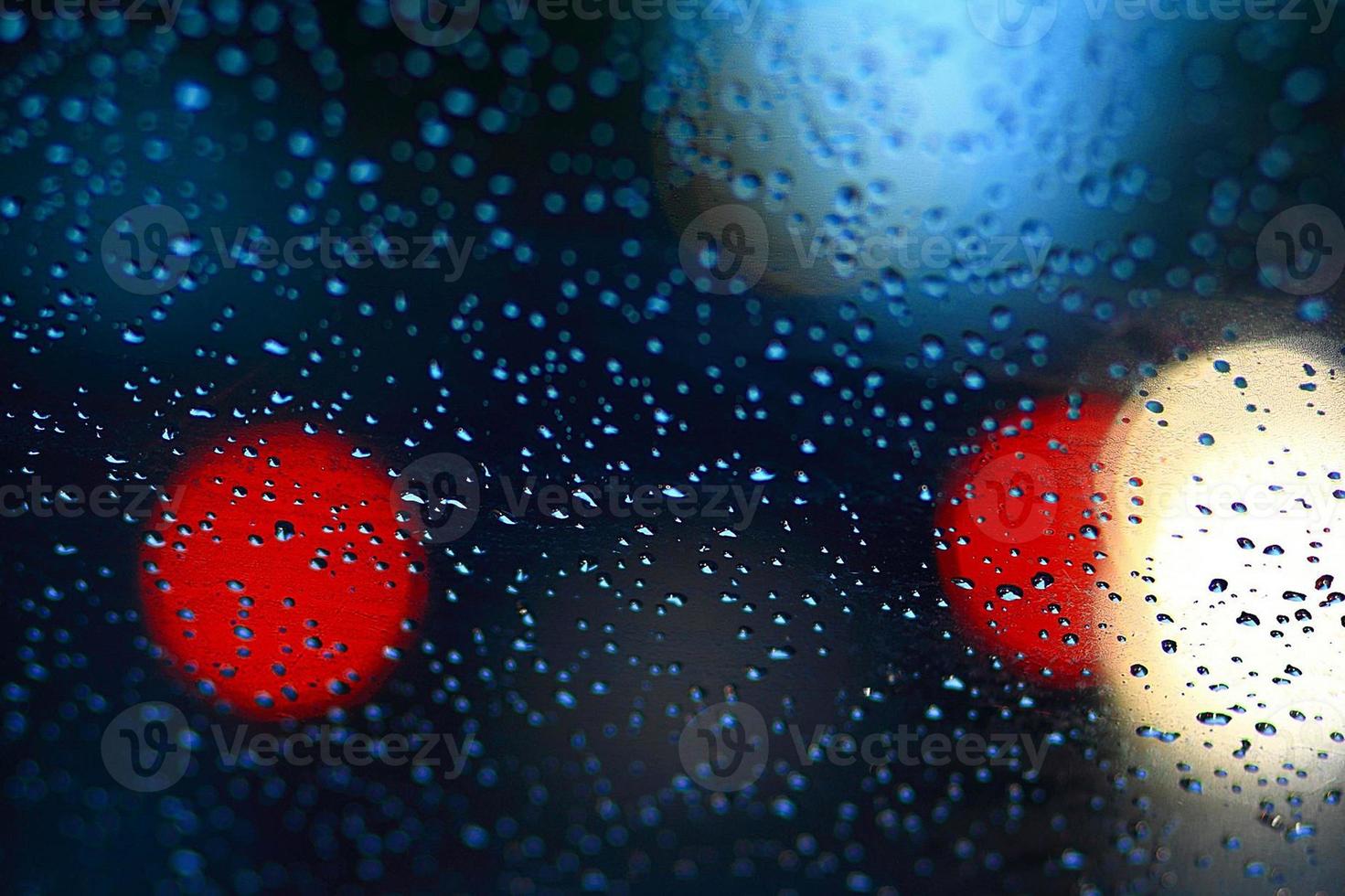 regendruppels op autoglas en kleurrijk bokeh-verkeerslicht foto