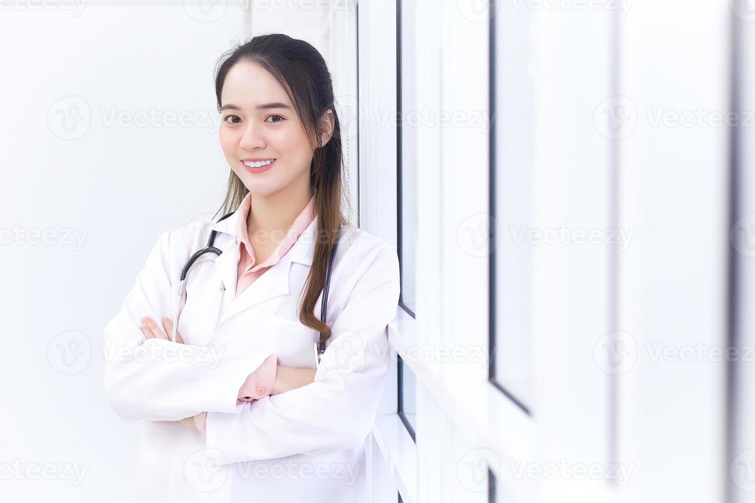 Aziatische vrouwelijke arts met zwart lang haar draagt een witte laboratoriumjas en stethoscoop. foto