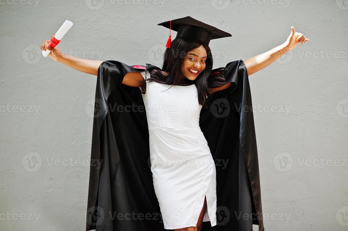 jonge vrouwelijke Afro-Amerikaanse student met diploma poseert buitenshuis. foto