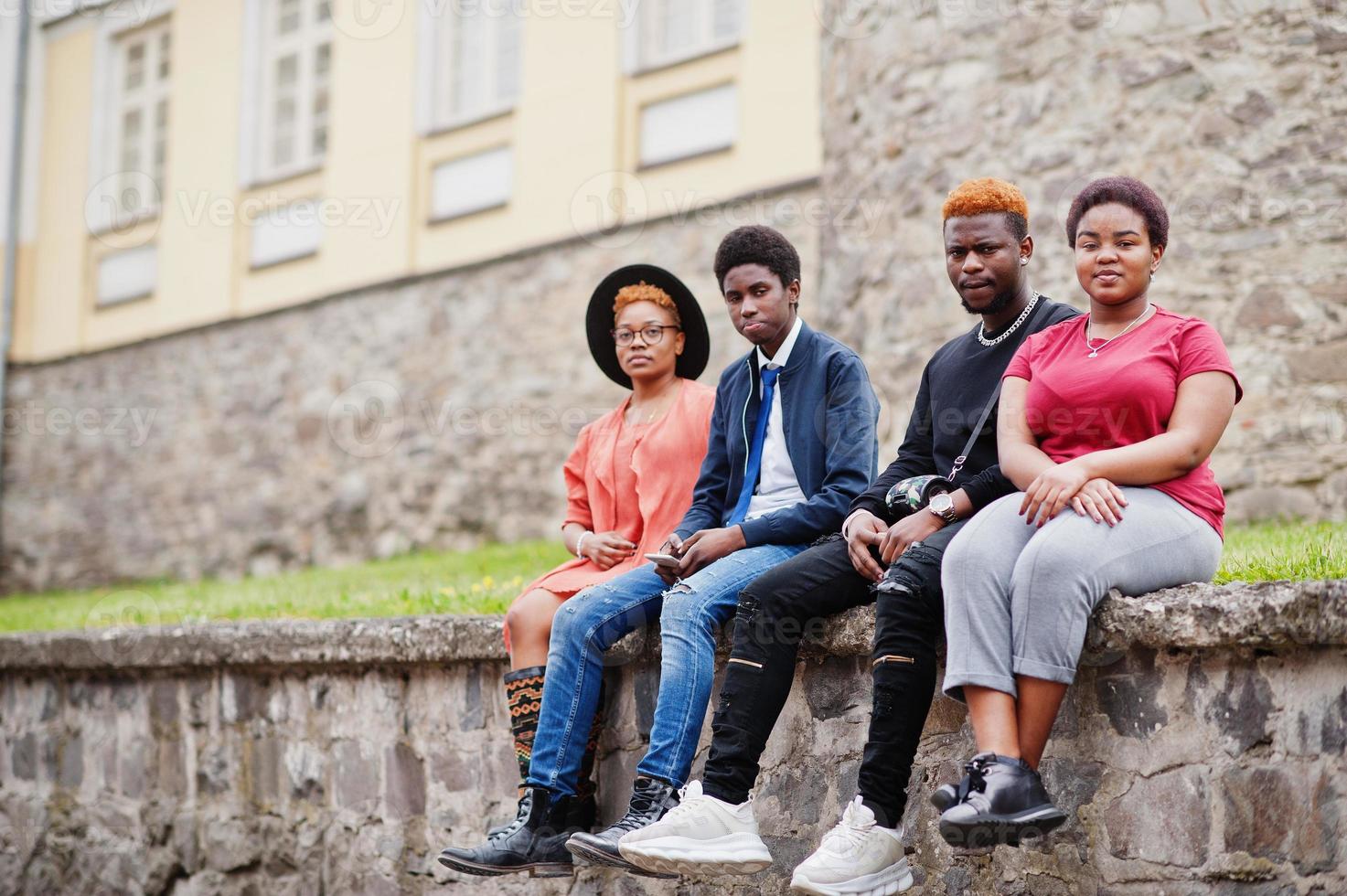vier Afrikaanse vrienden die buiten plezier hebben. twee zwarte meisjes met jongens zitten in een oude stad. foto