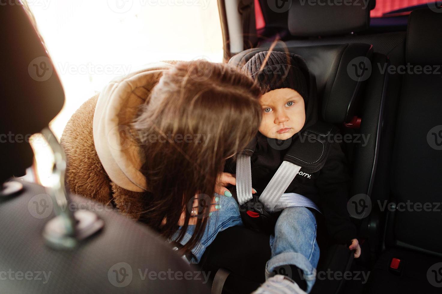 jonge moeder en kind in auto. kinderzitje op stoel. veiligheid rijden concept. foto