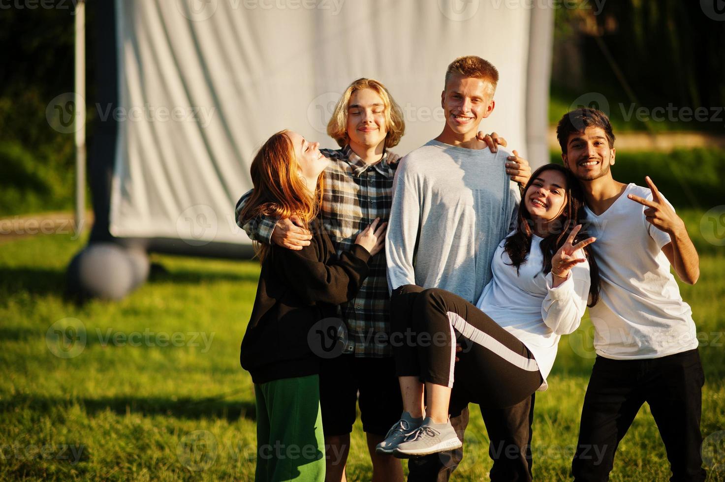 jonge multi-etnische groep mensen kijken naar film op poef in openluchtbioscoop. foto